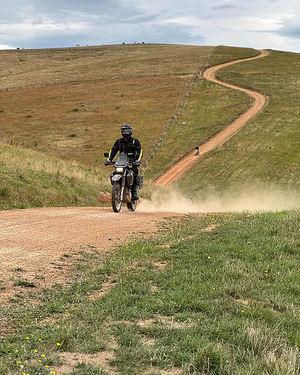 DR650 rider cresting a dirt road in the Victorian High Country, dust trailing behind